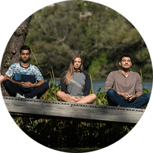 three people meditating outdoors