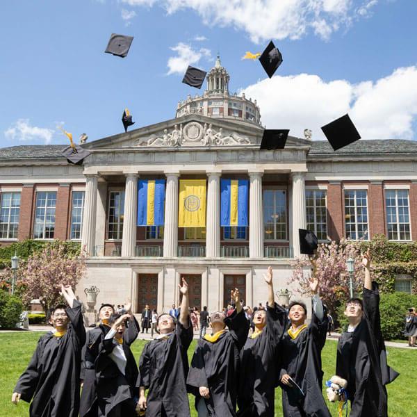 罗彻斯特大学周末毕业典礼后，学生们将毕业帽抛向空中.