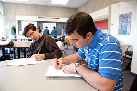 Two students sitting at a table taking notes.