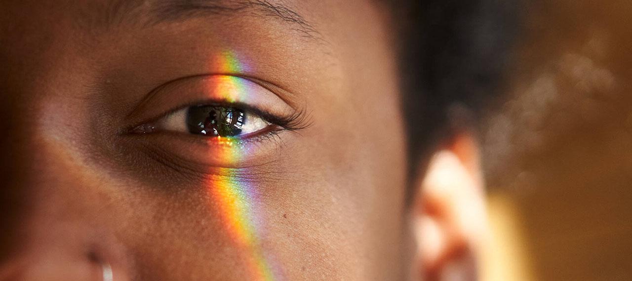 一个黑人眼睛的特写，多色的光线照在上面，说明视网膜神经节细胞是如何运作的.